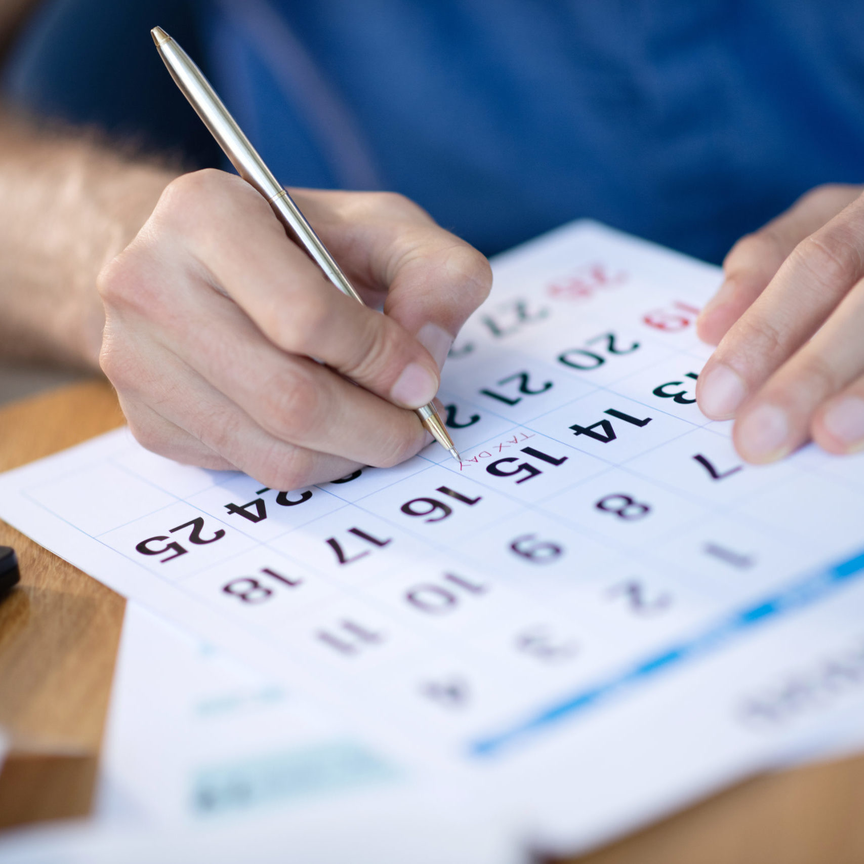 Businessman near calendar working on schedule Working on schedule. Businessman making some notes on calendar while working on schedule